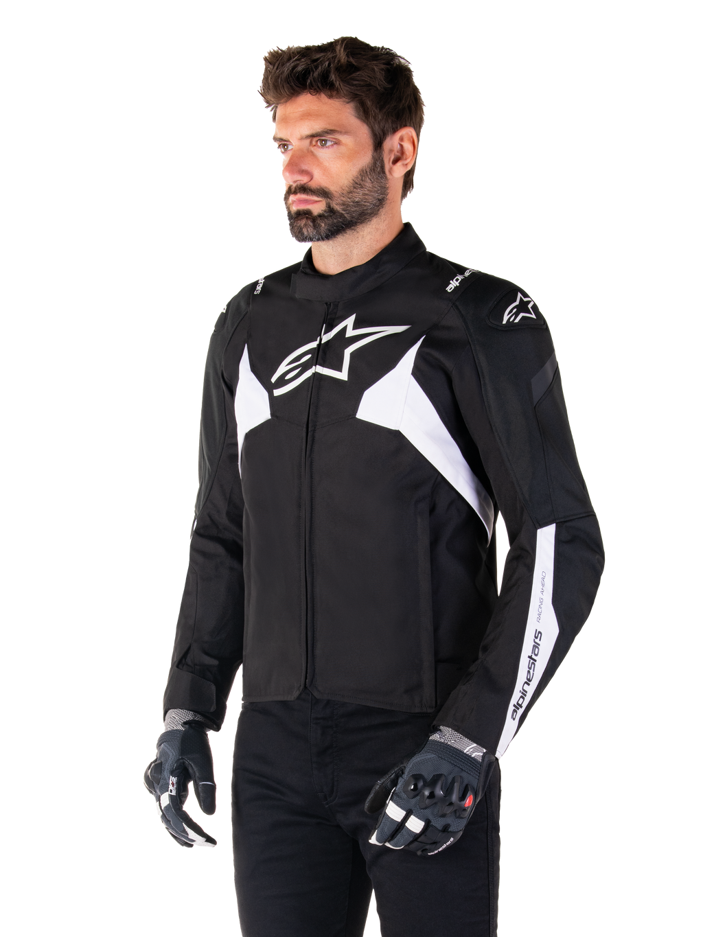 Alpinestars T-Jaws V4 Waterproof Jacket, zwart en wit, gedragen door een model met motorhandschoenen, met opvallende witte Alpinestars-logo's en accenten, sportieve textiele motorjas voor op de weg