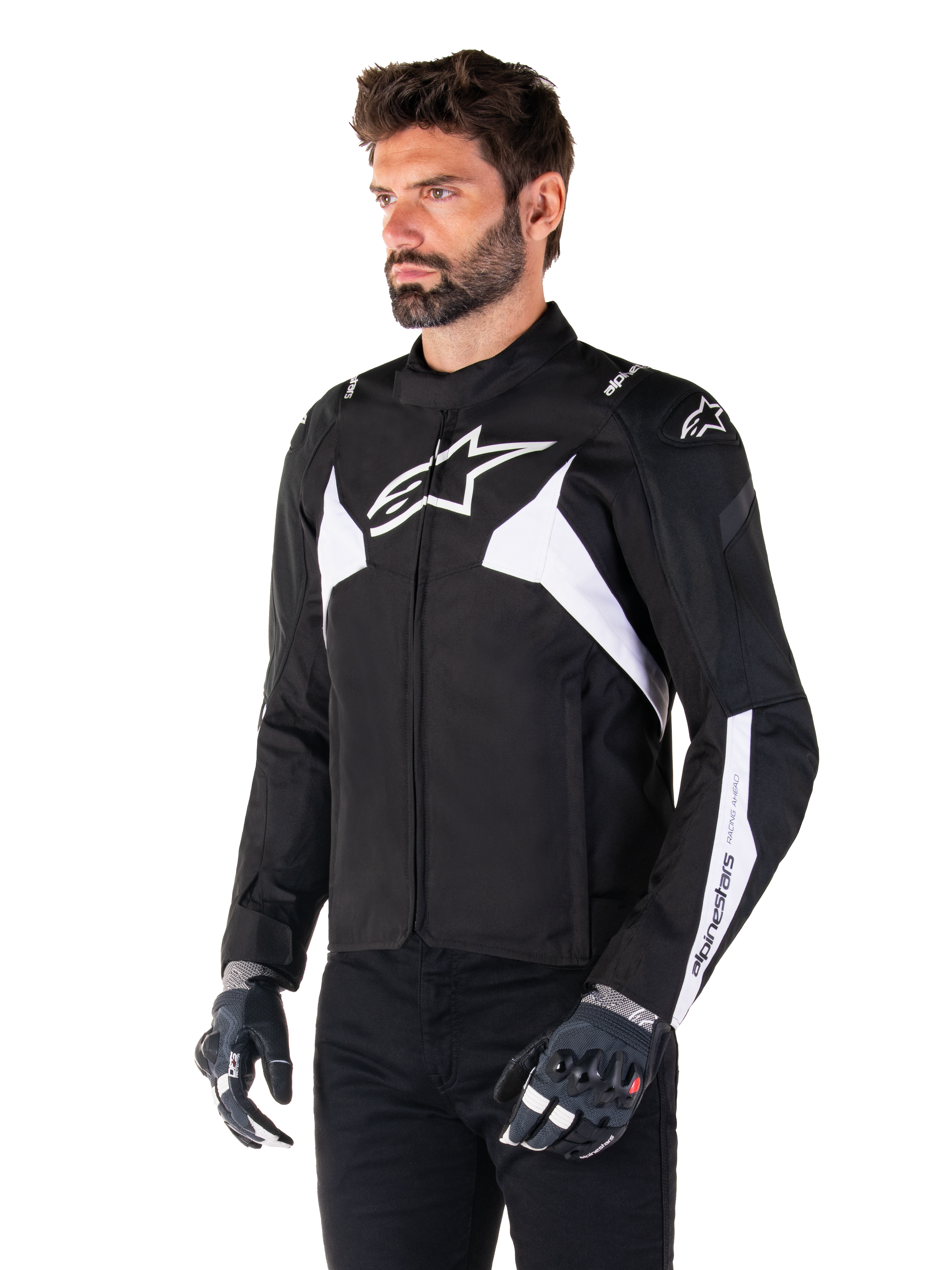 Alpinestars T-Jaws V4 Waterproof Jacket, zwart en wit, gedragen door een model met motorhandschoenen, met opvallende witte Alpinestars-logo's en accenten, sportieve textiele motorjas voor op de weg
