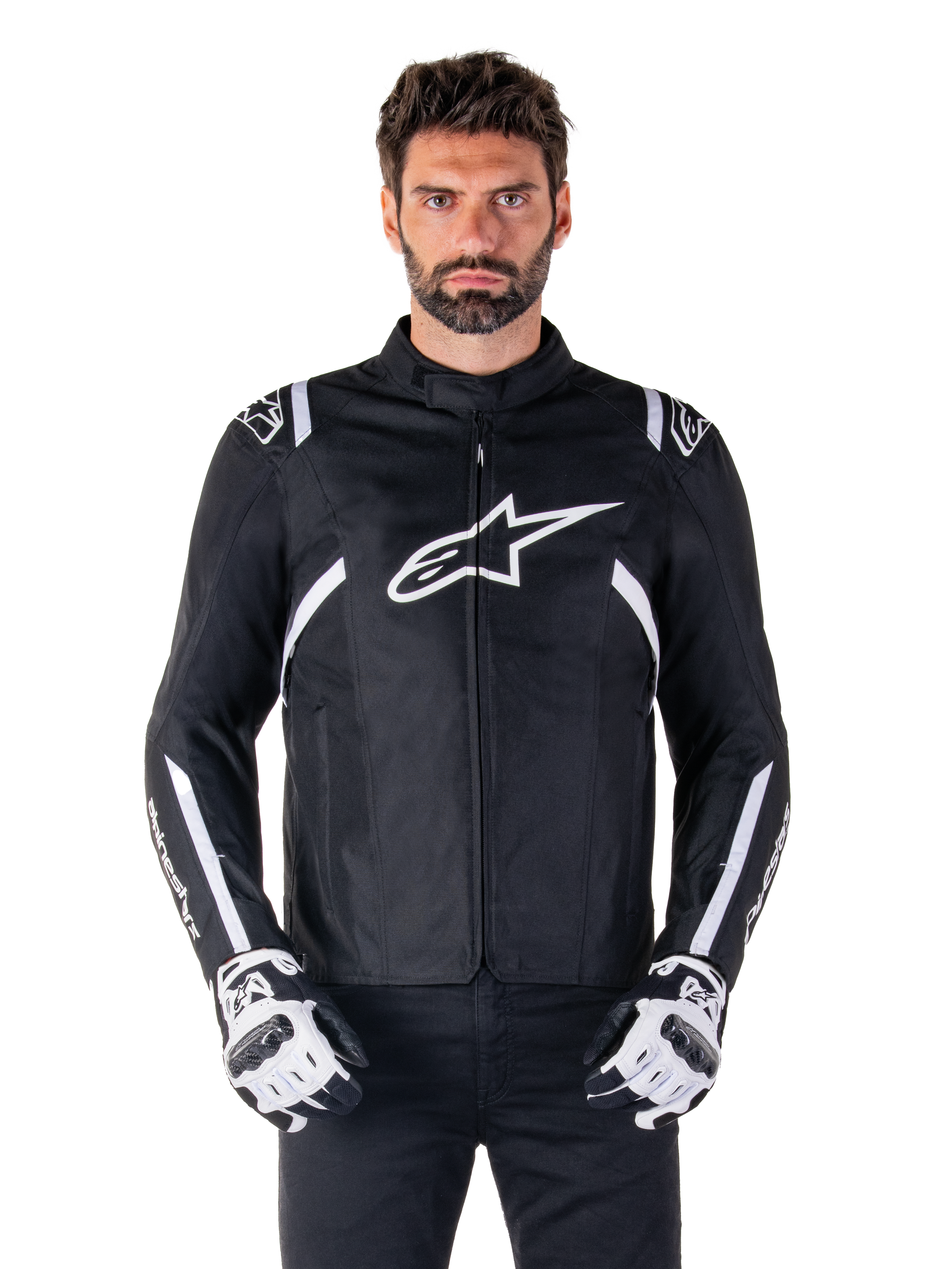 Alpinestars T-SPS V2 Waterproof Jacket in Black and White, front view on model, waterproof textile motorcycle jacket featuring white shoulder and arm stripes, large white Alpinestars logo on chest, worn with protective motorcycle gloves, sleek sport-inspired silhouette