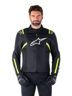 Veste imperméable Alpinestars T-SPS V2, veste de moto, noire avec des accents blancs et jaune fluo, portée par un mannequin avec des gants noirs, dotée d'un logo étoile blanc sur la poitrine et de bandes jaune fluo sur les manches et les épaules, équipement textile de style sport pour rouler par tous les temps