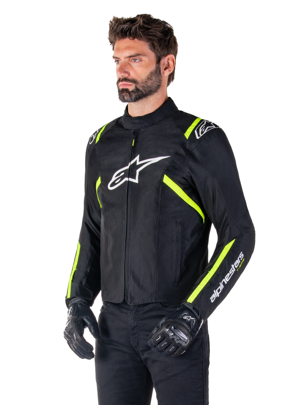 Mannequin homme portant la veste Alpinestars T-SPS V2 Waterproof, noire avec des accents blancs et jaune fluo, avec un logo Astars blanc sur la poitrine et des bandes jaune fluo sur les épaules et les manches, associée à un pantalon noir et des gants de moto, veste de moto en textile à coupe sport.