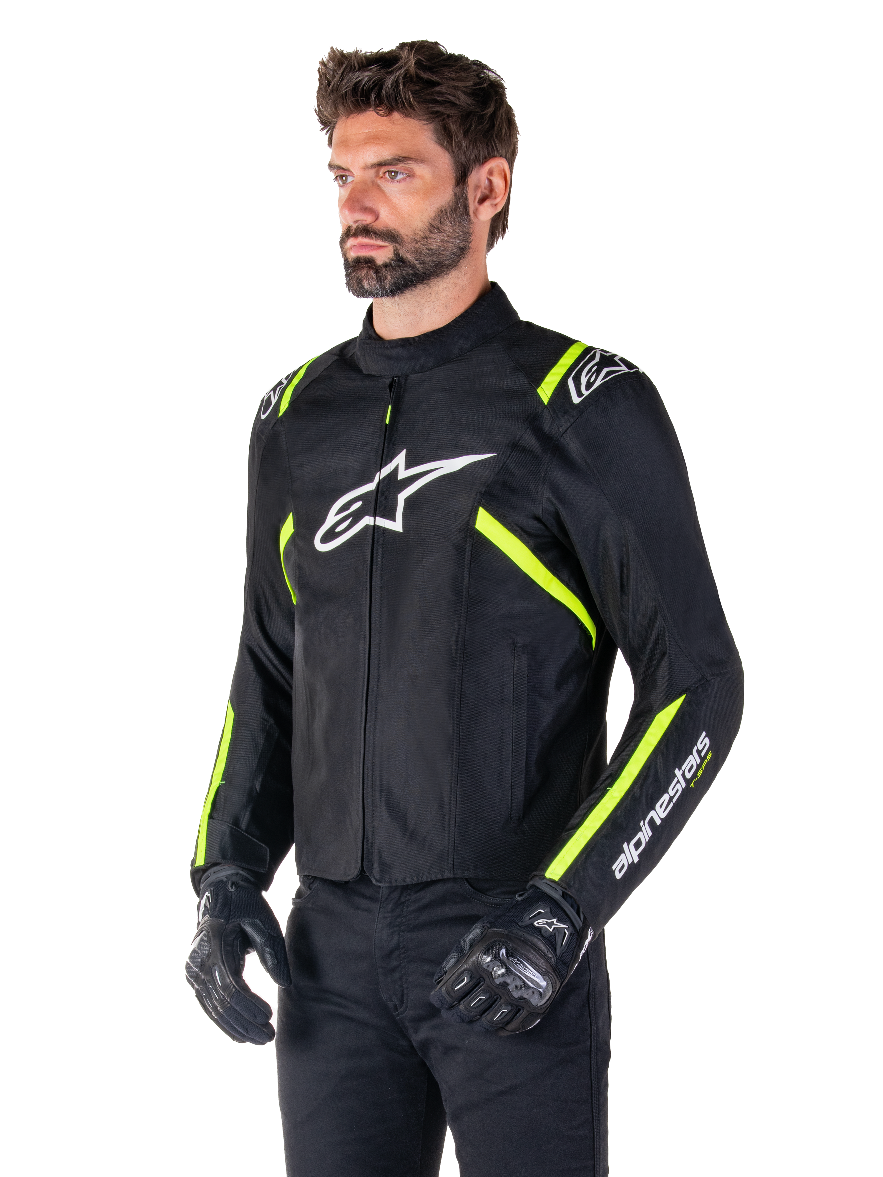 Mannequin homme portant la veste Alpinestars T-SPS V2 Waterproof, noire avec des accents blancs et jaune fluo, avec un logo Astars blanc sur la poitrine et des bandes jaune fluo sur les épaules et les manches, associée à un pantalon noir et des gants de moto, veste de moto en textile à coupe sport.