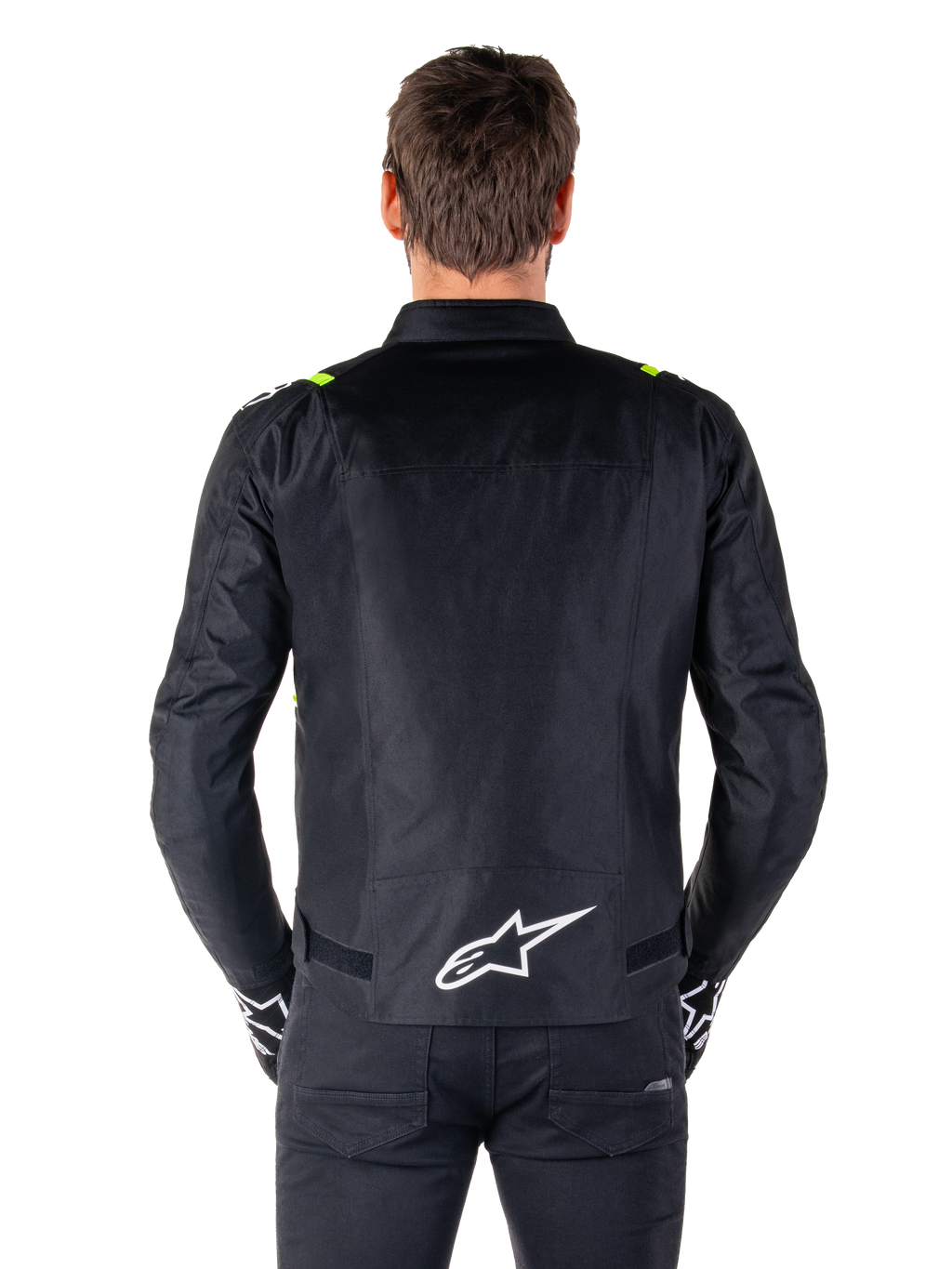 Veste imperméable Alpinestars T-SPS V2, vue de dos, noire avec des accents jaune fluo sur les épaules et logo étoile blanc dans le bas du dos, veste de moto en textile à la silhouette sport, portée par un mannequin homme