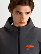 Alpinestars Aeroshell WP jas, heren motor sport softshell jas in zwart en donkergrijs, met capuchon en oranje ASTARS-logo, close-up van model