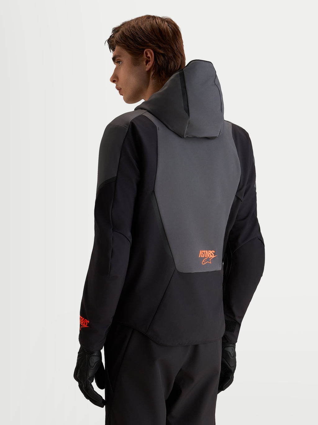 Alpinestars Aeroshell WP motorjas, waterdichte sportieve softshell motorjas voor heren, zwart en donkergrijs, met geïntegreerde capuchon en rugpaneeldetail, achteraanzicht.