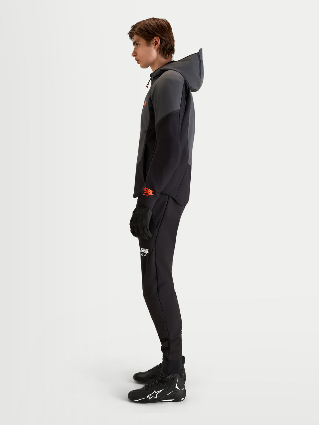 Alpinestars Aeroshell WP waterdichte motorjas, heren softshell hoodie in zwart en donkergrijs, met open capuchon en CE-gecertificeerde bescherming, gedragen door een model in profiel