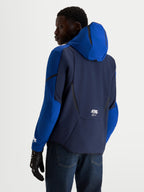 Alpinestars Aeroshell waterdichte herenmotorjas, nachtblauw en felblauw, softshell motorjas met vaste capuchon, achteraanzicht op model met motorhandschoenen
