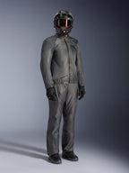 Motard portant la veste Alpinestars Borrego Drystar® en Warm Gray, équipement d'aventure complet avec pantalon gris assorti, casque intégral noir avec lunettes et gants noirs, doté d'un design élégant en textile imperméable.