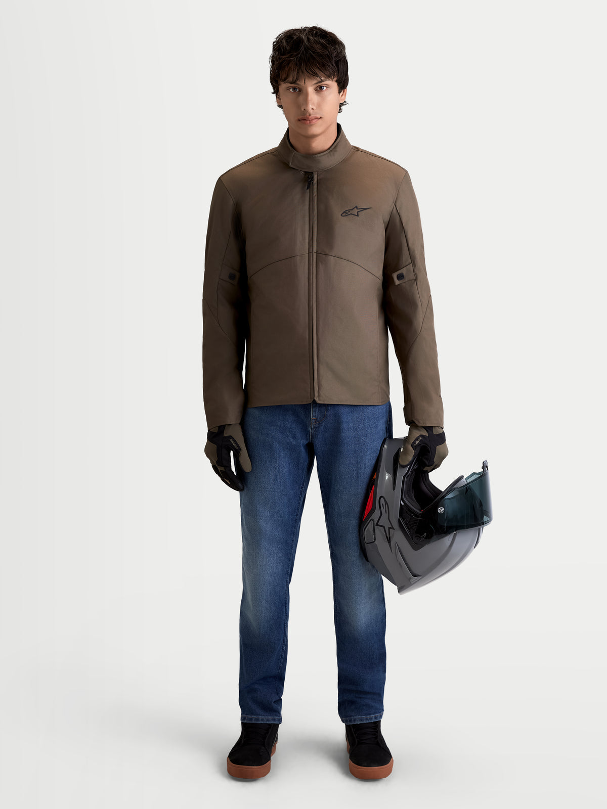 Alpinestars Veste C-1 Waterproof, veste de moto urbaine contemporaine pour homme, marron noyer et noire, vue de face sur un modèle portant la veste et tenant un casque, équipement de protection imperméable