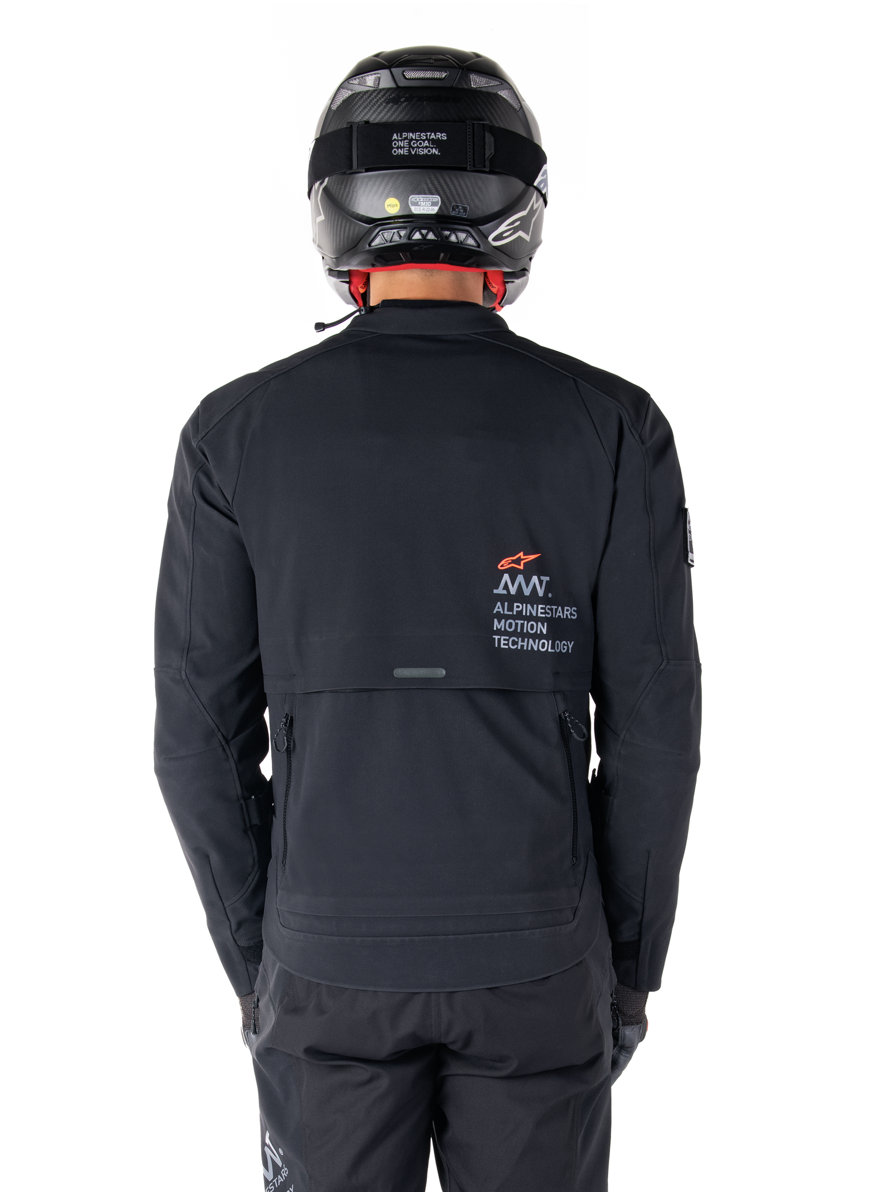 Alpinestars AMT-8 Stretch Drystar® XF Jacke, Rückansicht, Schwarz, getragen mit schwarzem Helm und Hose, mit Alpinestars Motion Technology Branding auf dem Rücken, Adventure-Touring-Design aus ergonomischem Stretchmaterial.