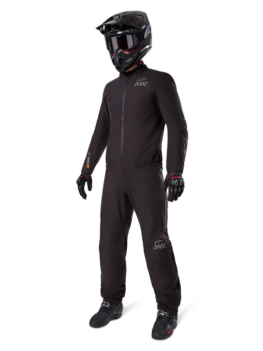 Alpinestars AMT-8 Stretch Drystar® XF Liner, schwarzer wasserdichter Motorradanzug, getragen mit schwarzem Helm, Schutzbrille und Handschuhen, mit AMT- und Drystar XF-Branding, funktionale Adventure-Ausrüstung für Allwetterschutz.