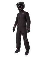 Alpinestars AMT-8 Stretch Drystar® XF Liner, schwarzer wasserdichter Motorradanzug, getragen mit schwarzem Helm, Schutzbrille und Handschuhen, mit AMT- und Drystar XF-Branding, funktionale Adventure-Ausrüstung für Allwetterschutz.