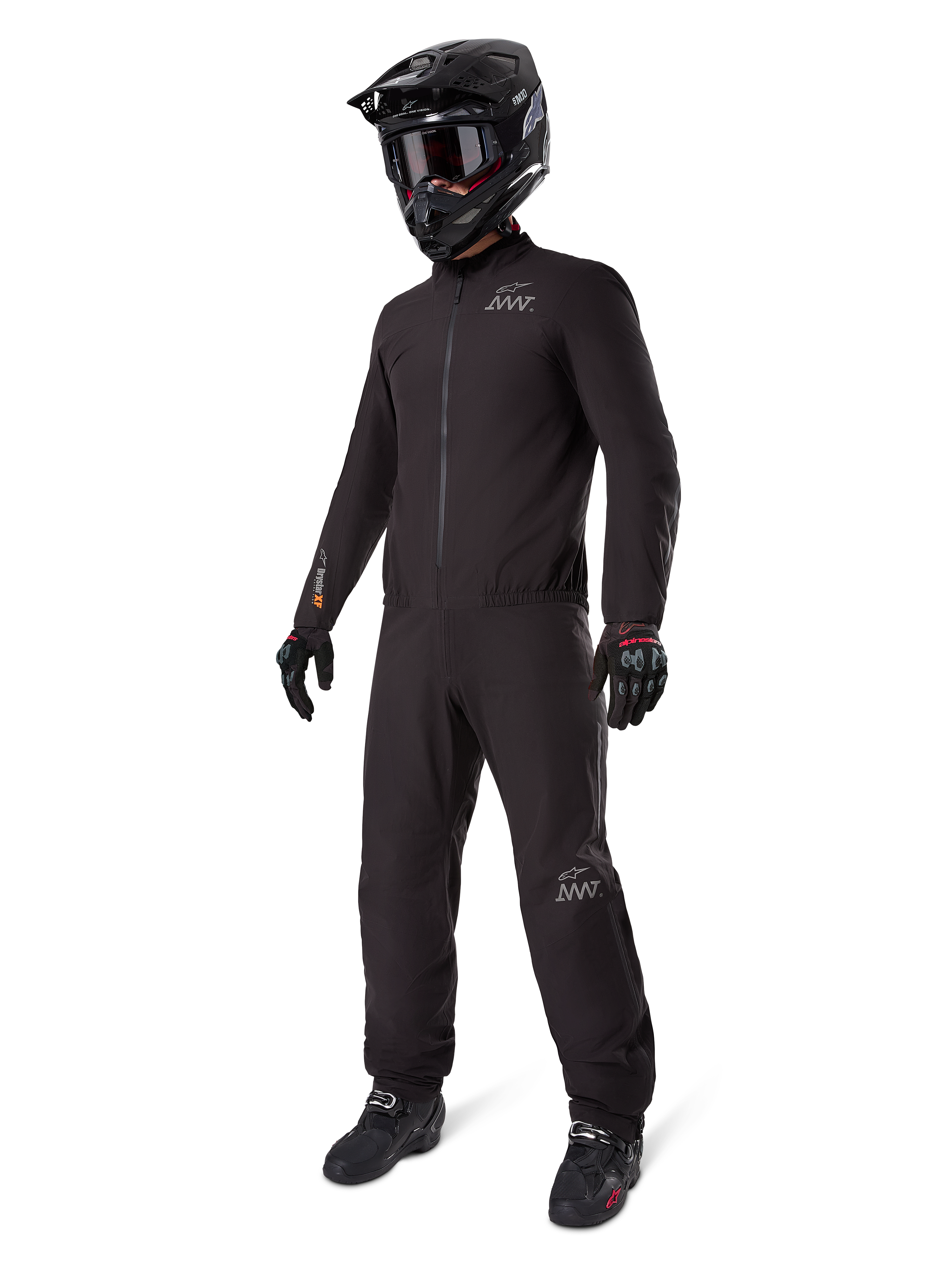 Alpinestars AMT-8 Stretch Drystar® XF Liner, schwarzer wasserdichter Motorradanzug, getragen mit schwarzem Helm, Schutzbrille und Handschuhen, mit AMT- und Drystar XF-Branding, funktionale Adventure-Ausrüstung für Allwetterschutz.