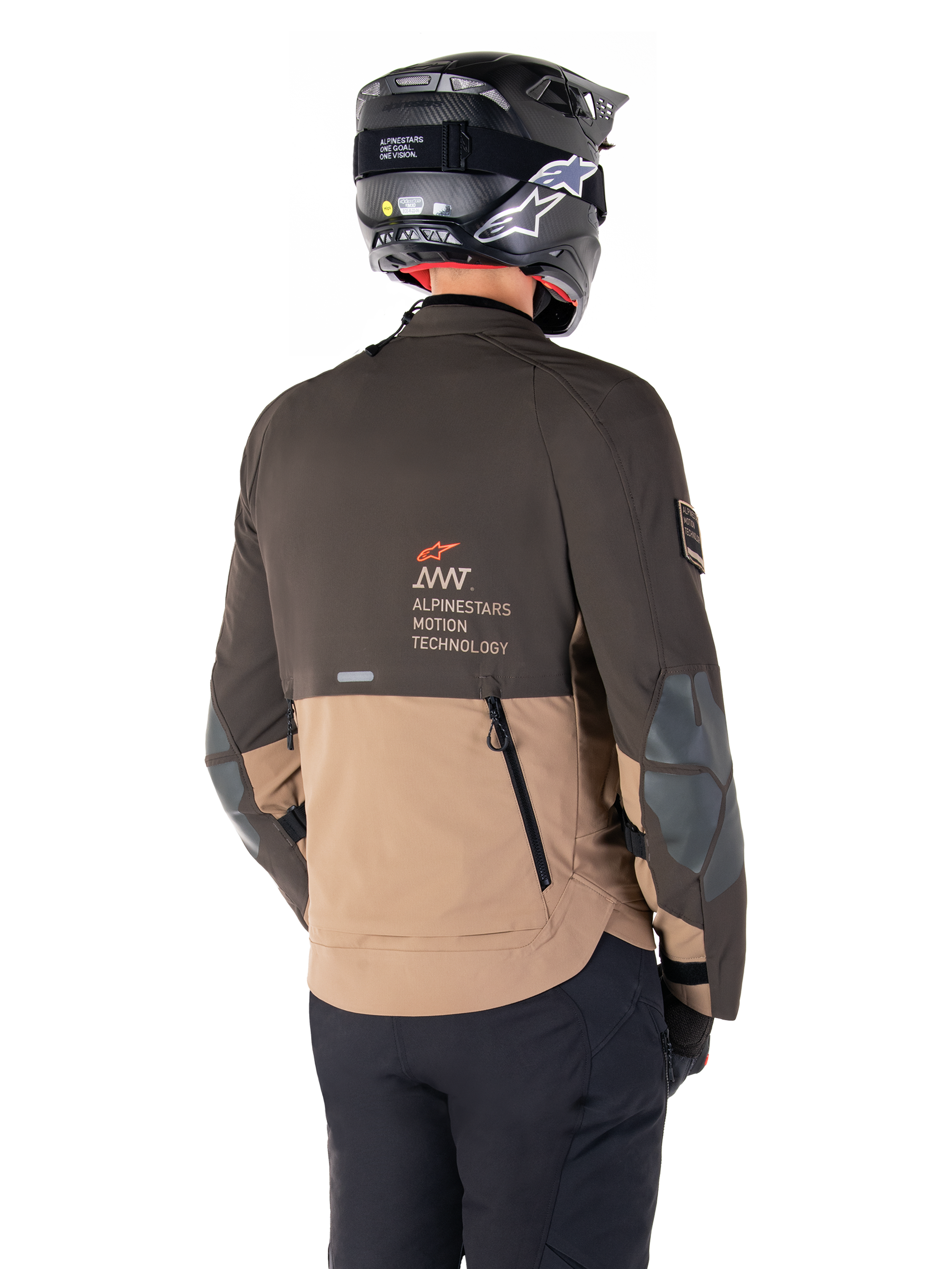Veste Alpinestars AMT-8 Stretch Drystar® XF, veste de moto d'aventure, brun foncé et kaki foncé, vue arrière montrant le marquage AMT Alpinestars Motion Technology, design textile bicolore avec fermetures éclair de ventilation à l'arrière et échappement en bardeaux, portée avec un casque noir et un pantalon de moto