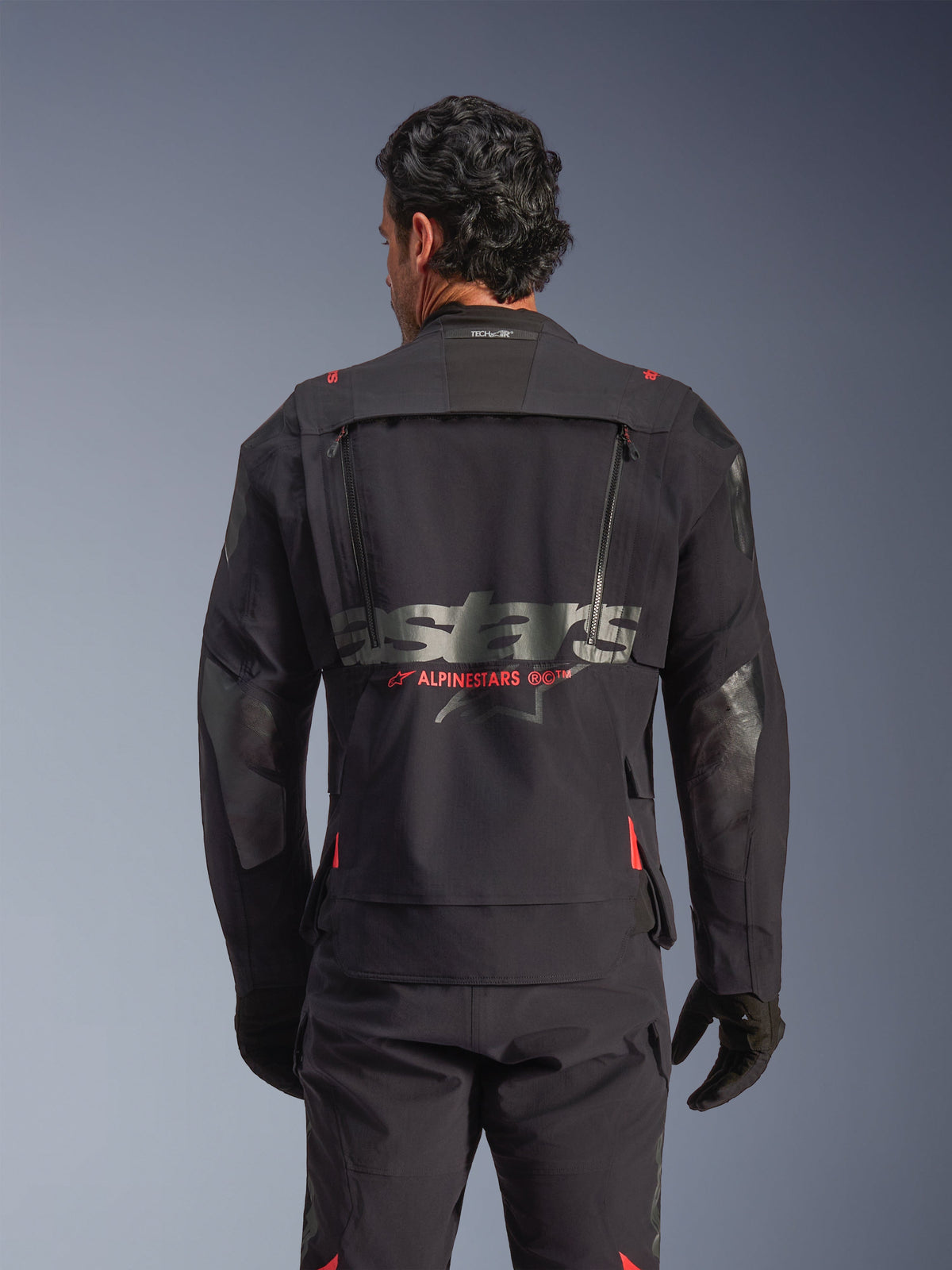 Veste laminée Alpinestars Halo Pro Drystar® XF en Noir Dark Shadow, vue arrière sur mannequin, montrant le panneau de ventilation technique au dos avec fermetures éclair, les accents rouges du logo Alpinestars et le marquage Tech-Air® sur la nuque, équipement de moto aventure modulaire.