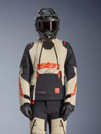 Alpinestars Halo Pro Drystar XF Laminated Jacket, adventure motorcycle jacket in Mastic Black and beige with red accents, worn with full protective gear including helmet and gloves, featuring modular ventilation panels and 3L laminated construction.