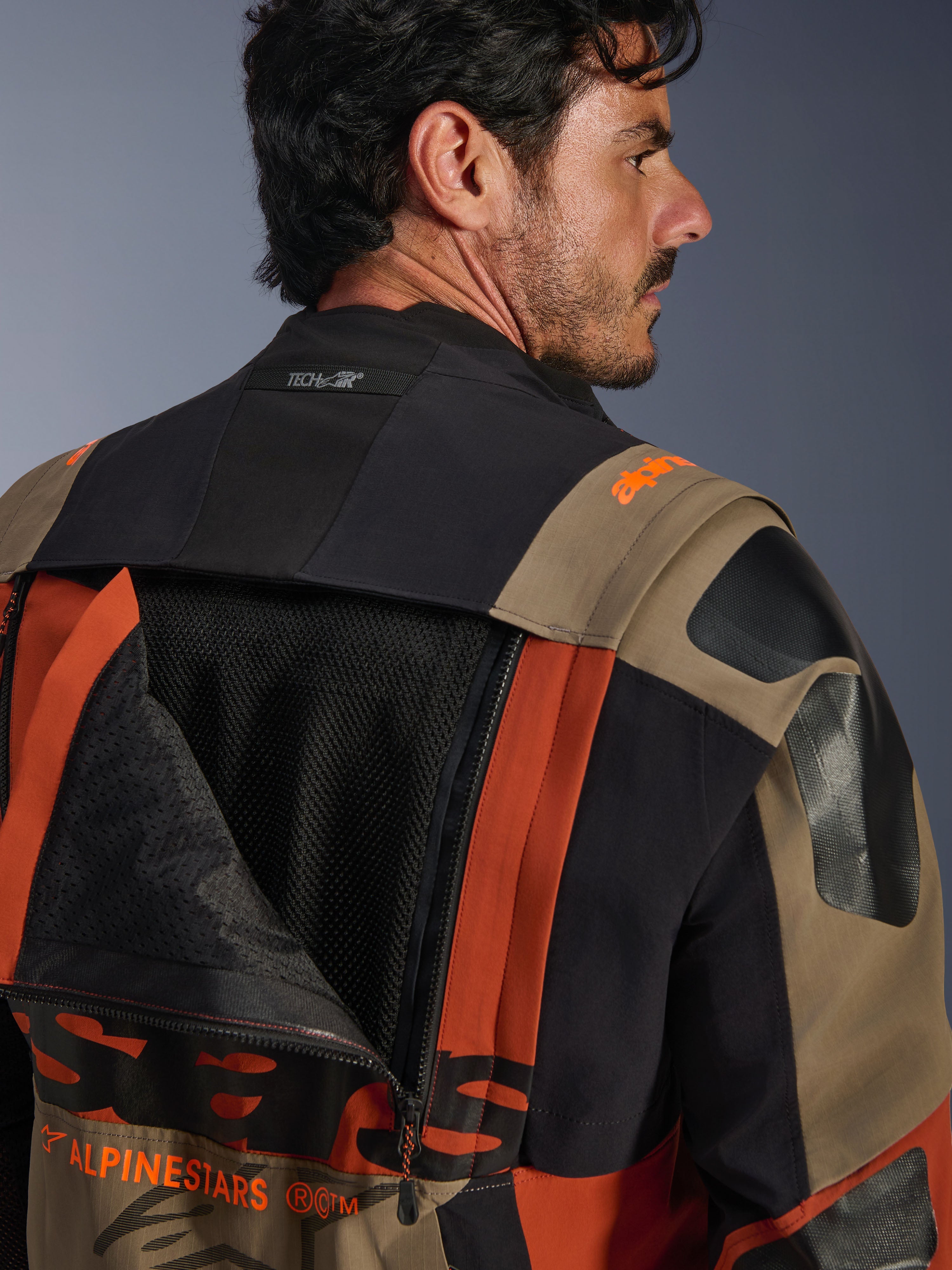 Alpinestars Halo Pro Drystar® XF gelamineerd jack in Walnut Rust Black, close-up achteraanzicht met een opengeritst ventilatiepaneel dat het interne mesh onthult, Tech-Air® branding op de kraag en een duurzame meerkleurige textielconstructie.