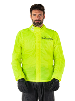 Alpinestars Hurricane Rain V2 Jacke, Motorrad-Regenjacke, Neongelb, getragen von einem Model mit schwarzer Hose und Handschuhen, hoher Kragen mit reflektierenden Laschen, vordere Sturmklappe mit Alpinestars-Logo, hochsichtbare wasserdichte Ausrüstung