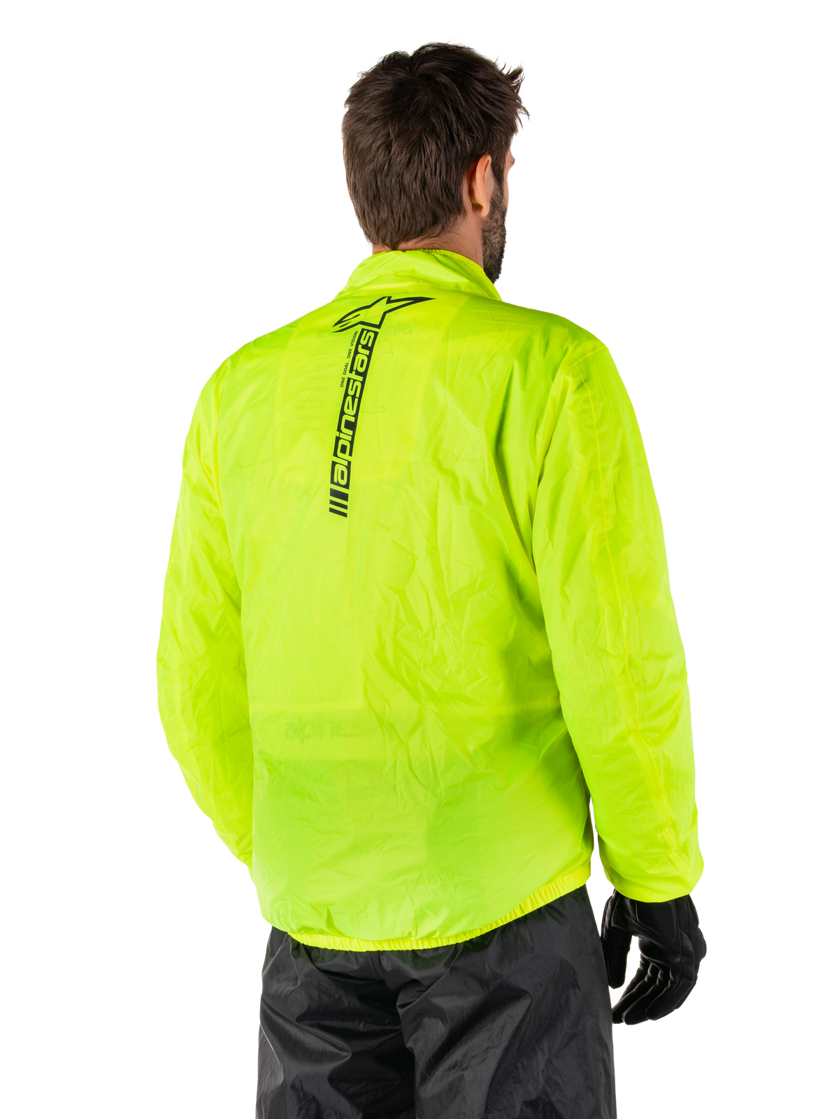 Veste Alpinestars Hurricane Rain V2, jaune fluo, vue arrière portée par un mannequin homme, logo Alpinestars vertical noir au centre du dos, taille et poignets élastiqués, conception imperméable et compacte