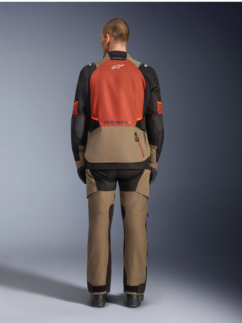 Veste Alpinestars Andes V4 Drystar®, Walnut Rust Black, vue arrière d'une veste de touring moto avec empiècement supérieur rouille et partie inférieure couleur noyer, portée avec un pantalon d'aventure assorti et des bottes noires