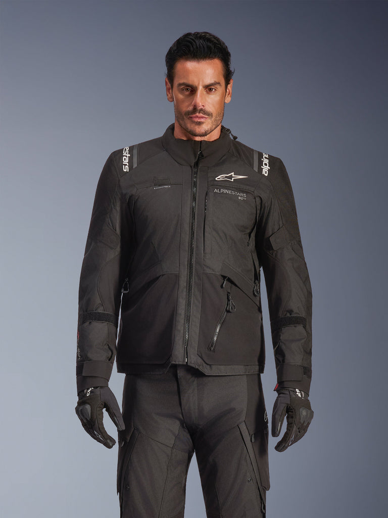 Alpinestars Andes V4 Drystar® Jacke in Schwarz, Adventure-Touren-Motorradjacke, kombiniert mit passender schwarzer Fahrhose und Handschuhen, wasserdichte Reißverschlüsse, weißes Alpinestars-Branding auf Brust und Schultern, Studioaufnahme für Allwetter-Fahrausrüstung