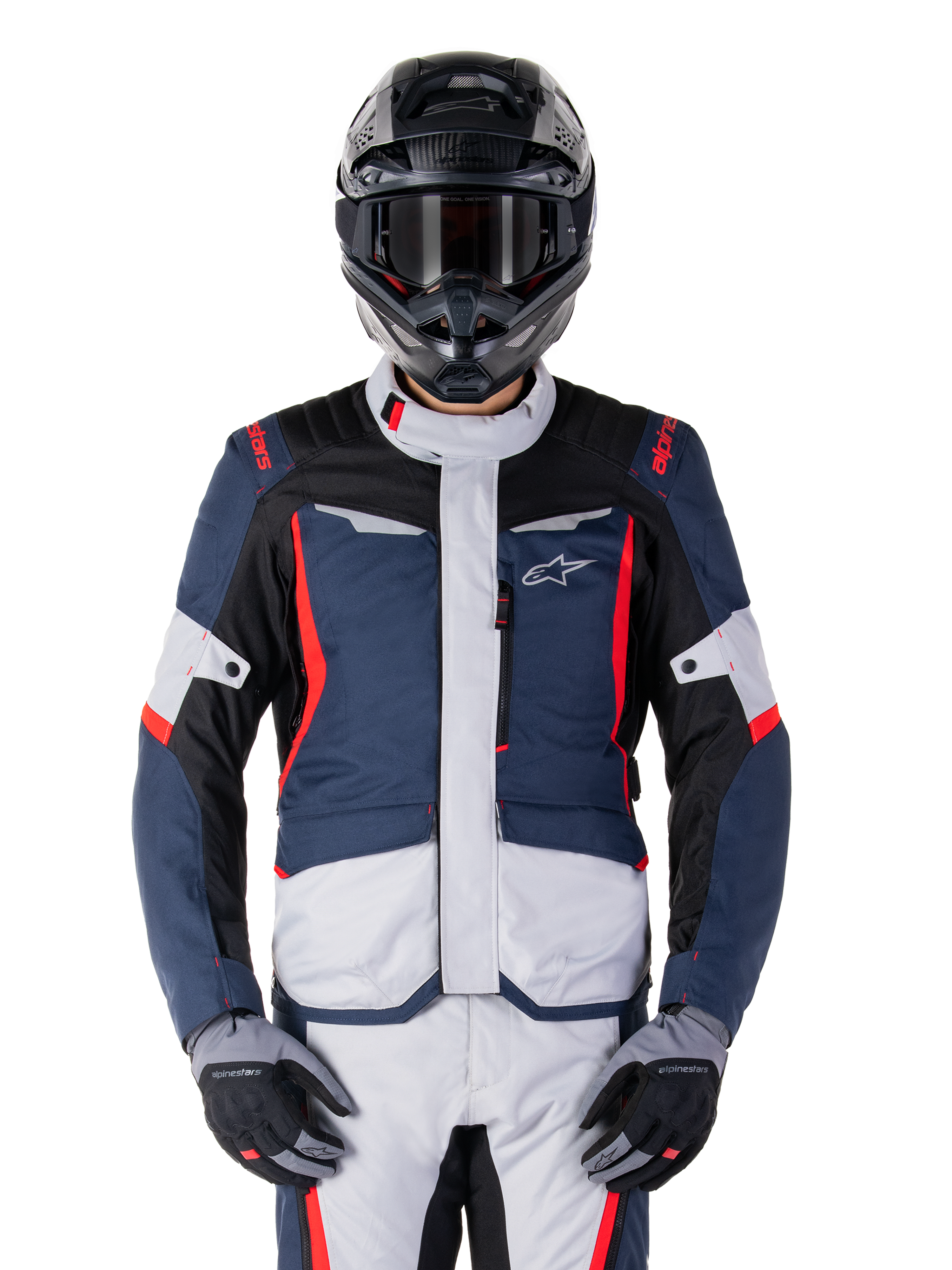 Veste imperméable Alpinestars ST-1, veste de tourisme d'aventure, bleu foncé, noir et rouge vif, portée avec un casque d'aventure noir et des gants gris, avec empiècements gris clair et accents rouges sur les épaules et les fermetures éclair, design épuré avec logo Alpinestars sur la poitrine, équipement de moto imperméable durable