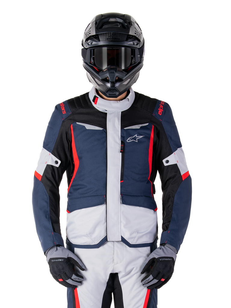 Alpinestars ST-1 Waterproof Jacket, Adventure Touring Jacket, Dark Blue Black and Bright Red, worn with a black adventure helmet and grey gloves, featuring light grey panels and red accents on shoulders and zippers, sleek design with Alpinestars branding on chest, durable waterproof gear for motorcycle riding