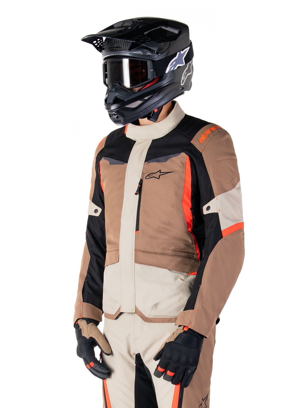 Alpinestars ST-1 Wasserdichte Jacke, Adventure-Touring-Jacke, Dark Khaki Sand Black und Red Fluo, getragen von einem Fahrer mit einem schwarzen Motocross-Helm und einer Brille, mit einem Multi-Panel-Design mit Cargo-Taschen und Alpinestars-Branding auf der Brust