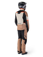 Alpinestars ST-1 Waterproof Jacke, Adventure-Touring-Jacke, Dark Khaki Sand Black Red Fluo, Rückansicht getragen mit passender Hose und schwarzem Helm, mit Color-Blocking-Einsätzen und fluoreszierenden roten Akzenten.