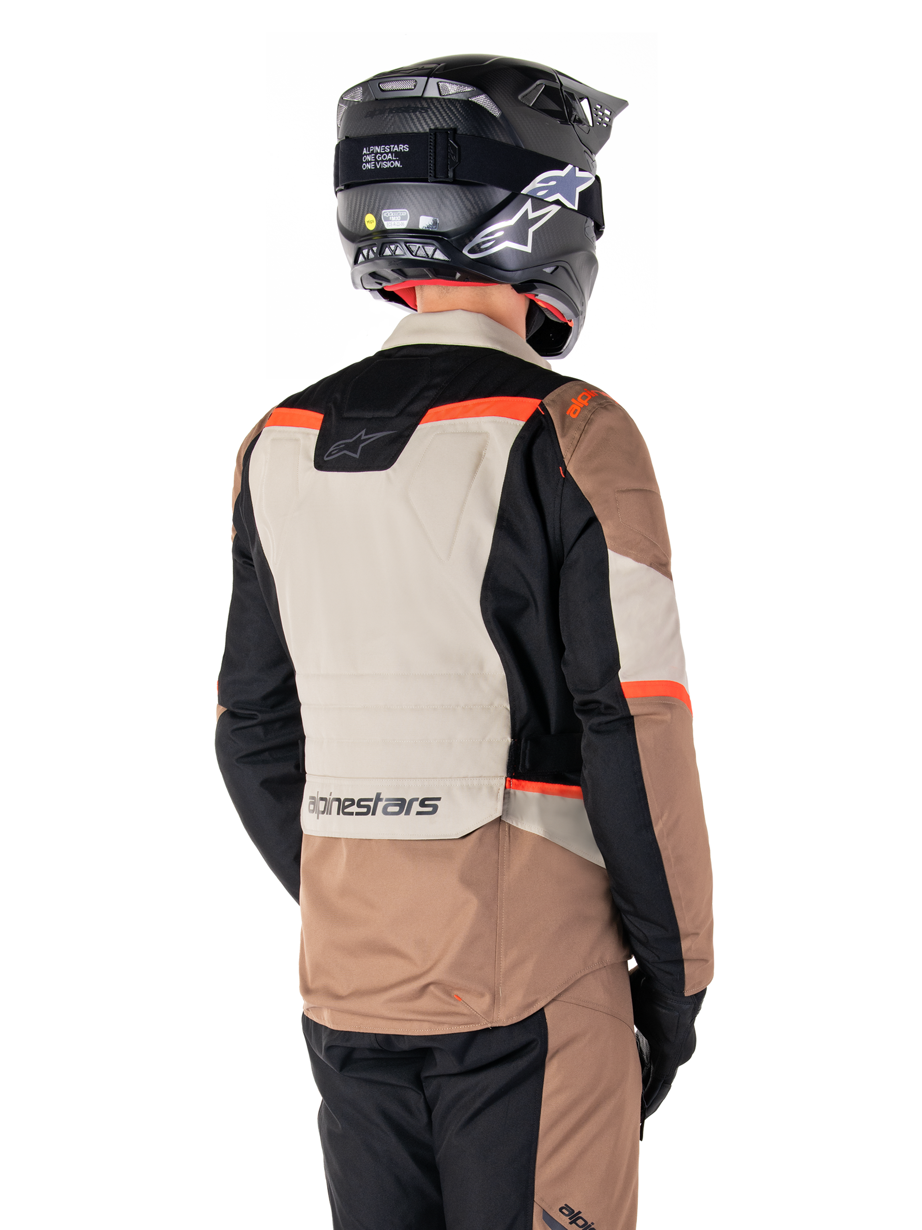 Alpinestars ST-1 Waterproof Jacke, Adventure-Touring-Jacke, Dark Khaki Sand Black Red Fluo, Rückansicht mit Textilpaneelen im Color-Block-Design, fluoreszierend roten Akzenten und Alpinestars-Branding am unteren Rücken, getragen von einem Fahrer mit schwarzem Helm.