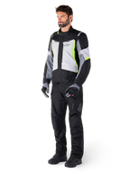 Alpinestars ST-1 Waterproof Jacket, Adventure Touring Motorcycle Jacket, Ice Gray Black and Yellow Fluo, worn by a model with matching black pants and gloves, featuring a streamlined design with bright yellow accents and Alpinestars branding.