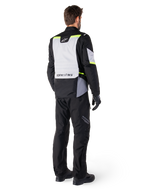 Alpinestars ST-1 Waterproof Jacket, adventure touring motorcycle jacket shown from the back, Ice Gray and Black with Yellow Fluo accents, worn with black riding pants and gloves, modern streamlined design with high-visibility fluorescent details and Alpinestars branding.