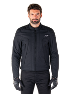 Alpinestars Clayton WR Jacket, zwarte motorjas, gedragen door een model, voorzien van gewatteerde schouderdetails en technische graphics, centrale Vislon-rits, verticale zakken met rits, klein wit logo op de borst, stedelijke motorkleding voor weggebruik