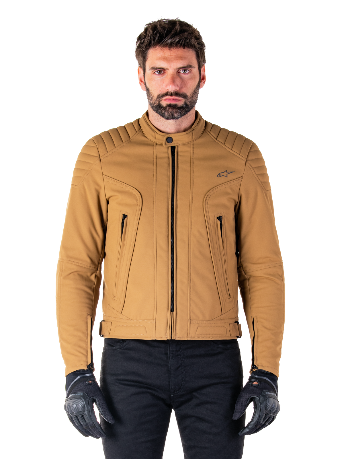 Alpinestars Clayton WR jas, urban motorjas, Utility Brown Light Gold, waterbestendig textiel met gewatteerde schouders, hoge kraag, zwarte ritsdetails en logo op de borst, gedragen met zwarte beschermende handschoenen en broek