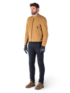Motard portant la veste Alpinestars Clayton WR en Utility Brown Light Gold, veste de moto urbaine contemporaine avec détails matelassés aux épaules, associée à un pantalon noir, des gants noirs et des bottes marron