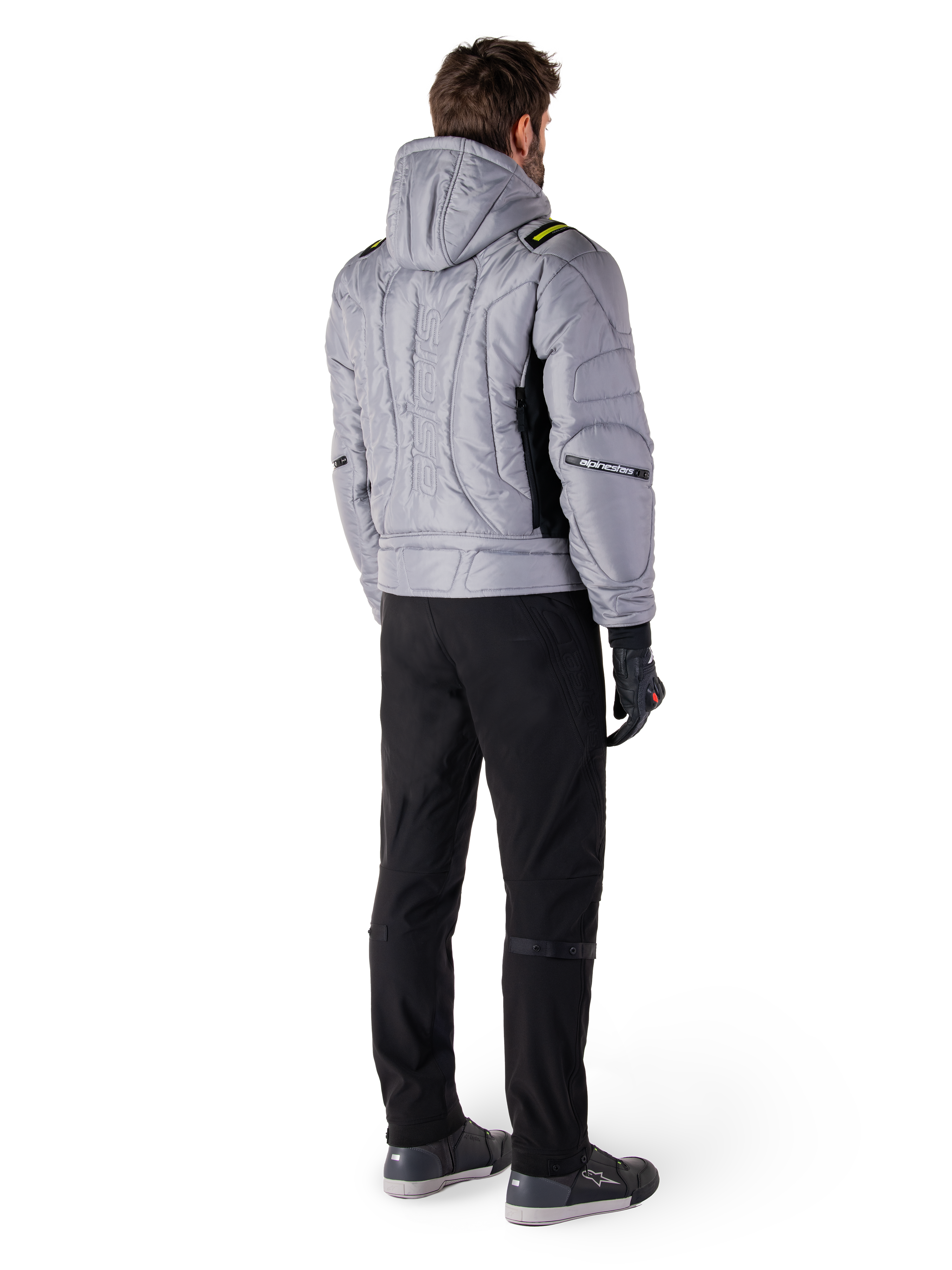 Alpinestars Mohobbs Wasserdichte Jacke, Lunar Gray Lime Punch, Rückansicht einer gesteppten Motorradjacke im Bomber-Stil mit Kapuze, mit Alpinestars-Schriftzug auf dem Rücken, getragen mit schwarzer Motorradhose und Handschuhen, urbane Moto-Streetwear