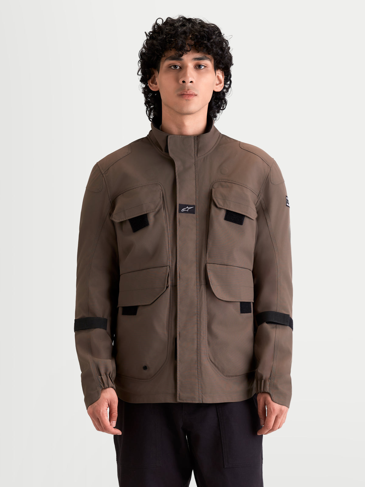 Alpinestars Altan Drystar Jacket, men's urban contemporary waterproof motorcycle jacket in walnut brown, front view worn by a model showing field-jacket storage pockets and warm collar construction