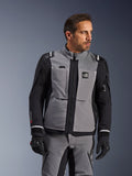 Alpinestars Andes Pro Drystar® XF Jacke in Dunkelgrau und Schwarz, Adventure-Motorradausrüstung, getragen von einem Mann mit passender grauer Hose und schwarzen Handschuhen, mit 3-Lagen-Laminat-Konstruktion, Funktionstaschen und „Terra“-Logo auf der Brust