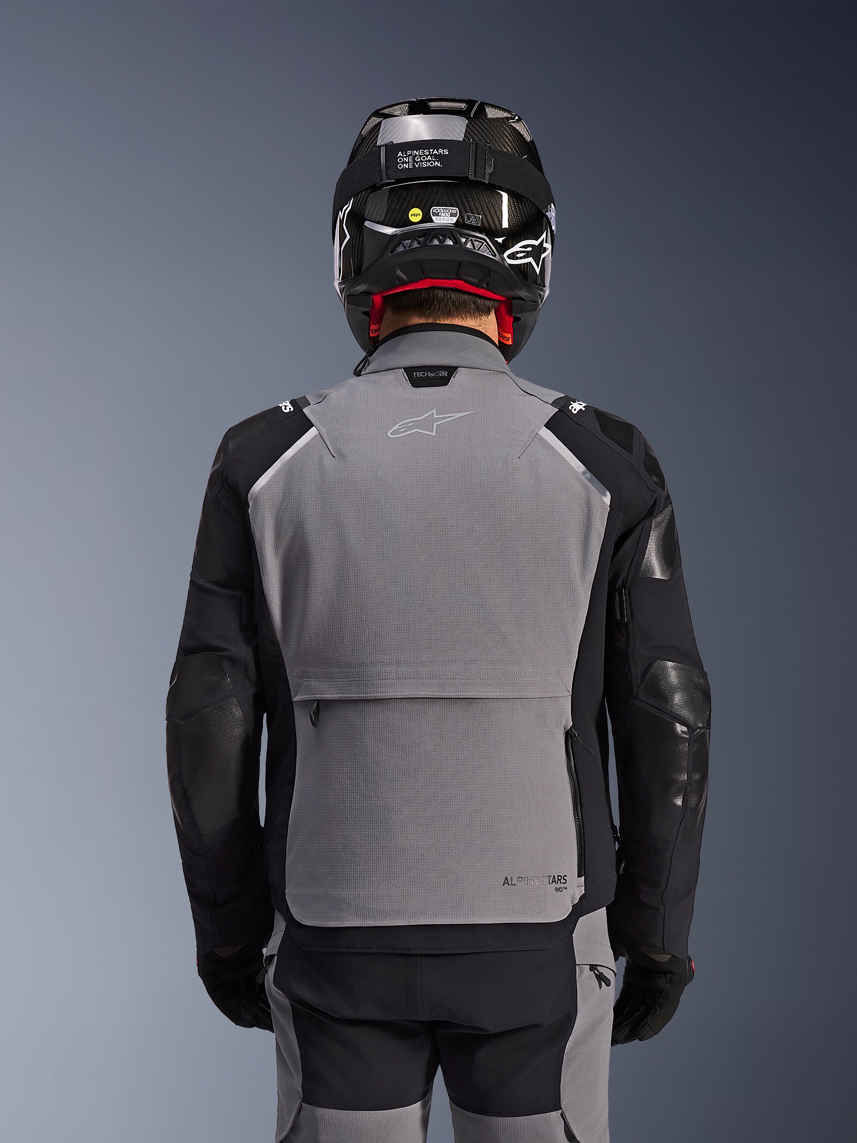 Alpinestars Andes Pro Drystar® XF Jacke, Dunkelgrau und Schwarz, Rückansicht mit großer Rückentasche und Tech-Air®-Branding, getragen von einem Fahrer mit schwarzem Helm und passender Hose, professionelle Adventure-Touring-Ausrüstung