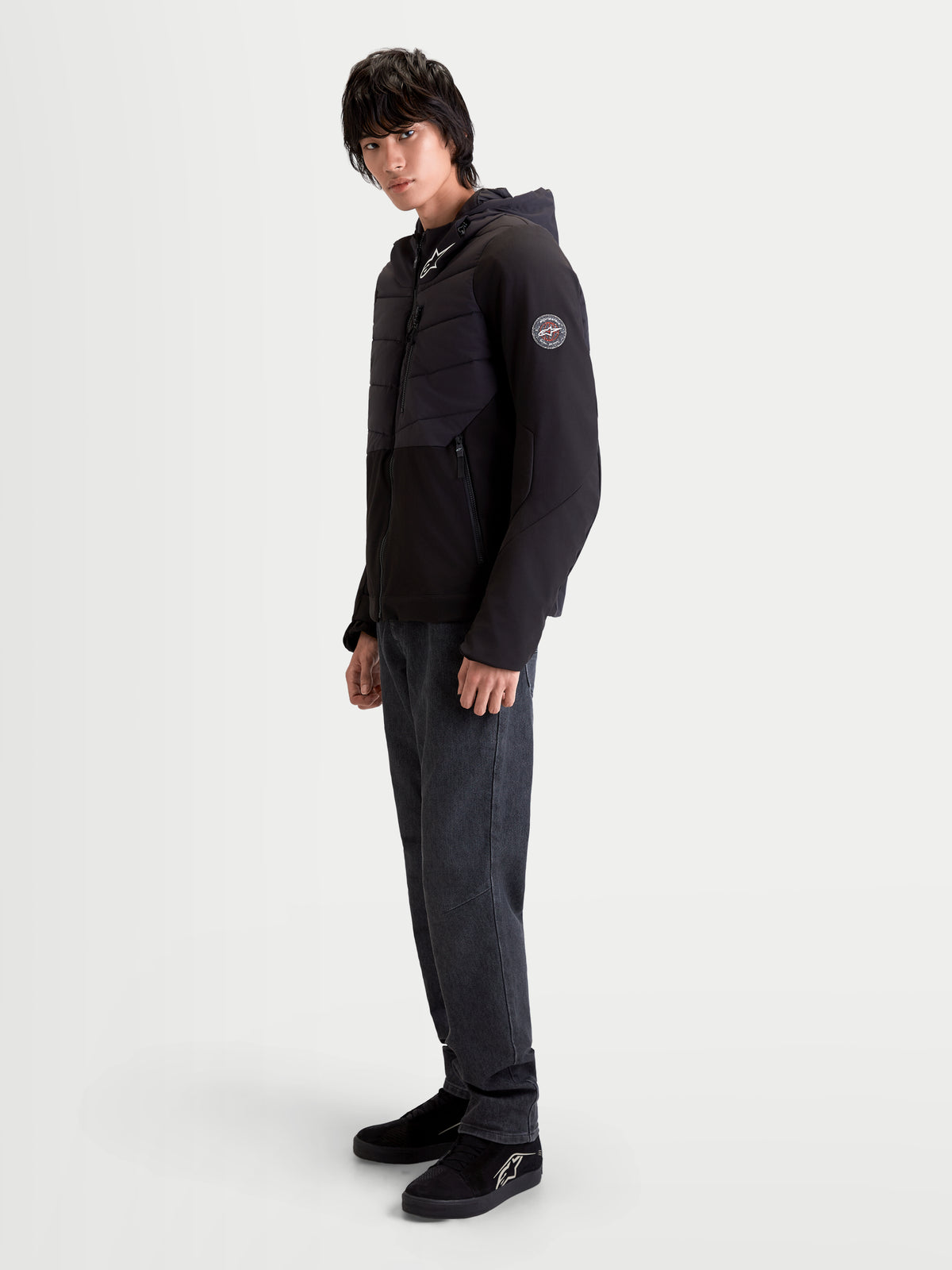 Alpinestars Therma Tech WP Veste, veste de moto urbaine contemporaine pour homme, noire, vue de profil latéral portée par un modèle montrant la construction matelassée et la capuche intégrée