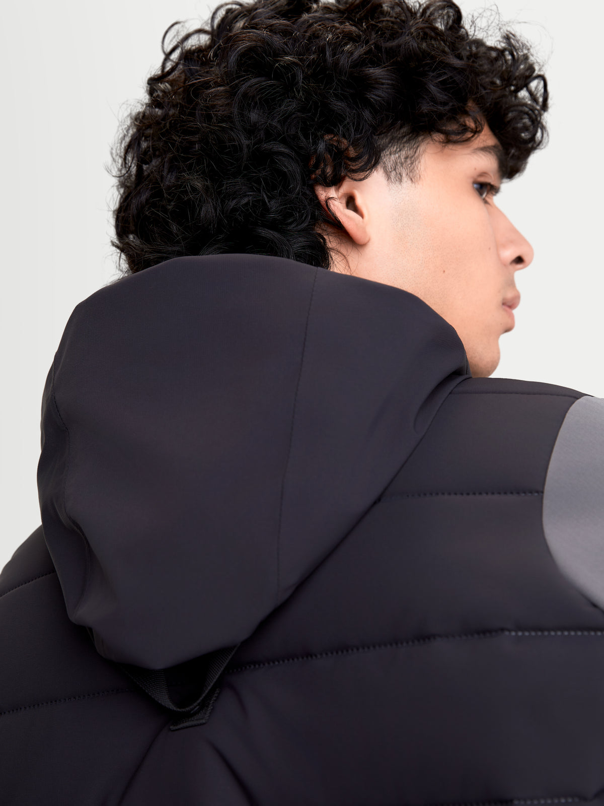 Alpinestars Therma-Tech Waterproof Jacket, urban motorjas voor heren in zwart en donkergrijs, achteraanzicht met de geïntegreerde capuchon en sonic-welded donsconstructie gedragen door een model