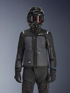 Veste Alpinestars Cusco Drystar®, noir et gris foncé, veste de moto adventure touring portée avec un pantalon technique noir assorti et un casque dual-sport, dotée d'un design bicolore avec empiècements en ripstop et marquage Alpinestars