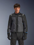 Veste Alpinestars Cusco Drystar®, veste de moto touring, noir et gris foncé, vue de face sur modèle, avec logos Alpinestars sur la poitrine et les épaules, marquage Drystar® sur la manche, design technique multi-poches avec zips de ventilation, associée à un équipement de moto noir
