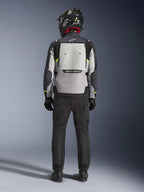 Motard vu de dos portant la veste Alpinestars Cusco Drystar® en Ice Gray, Mid Gray et Deep Gray, dotée d'un large panneau de ventilation dorsal et du logo Alpinestars, avec un pantalon de moto noir et un casque noir, équipement de moto adventure touring