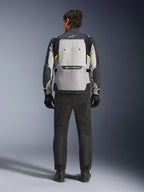 Vue arrière d'un motard portant la veste Alpinestars Cusco Drystar® en Ice Gray, Mid Gray et Deep Gray, associée à un pantalon et des gants de moto noirs, mettant en évidence le large panneau de ventilation arrière et le logo Alpinestars.