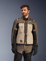 Alpinestars Cusco Drystar® Jacket, Adventure Motorcycle Jacket, Walnut Aluminum Black, worn by a model with black gloves, featuring tan chest panels and black sleeves with Alpinestars branding and All Terra patch, protective all-weather touring gear
