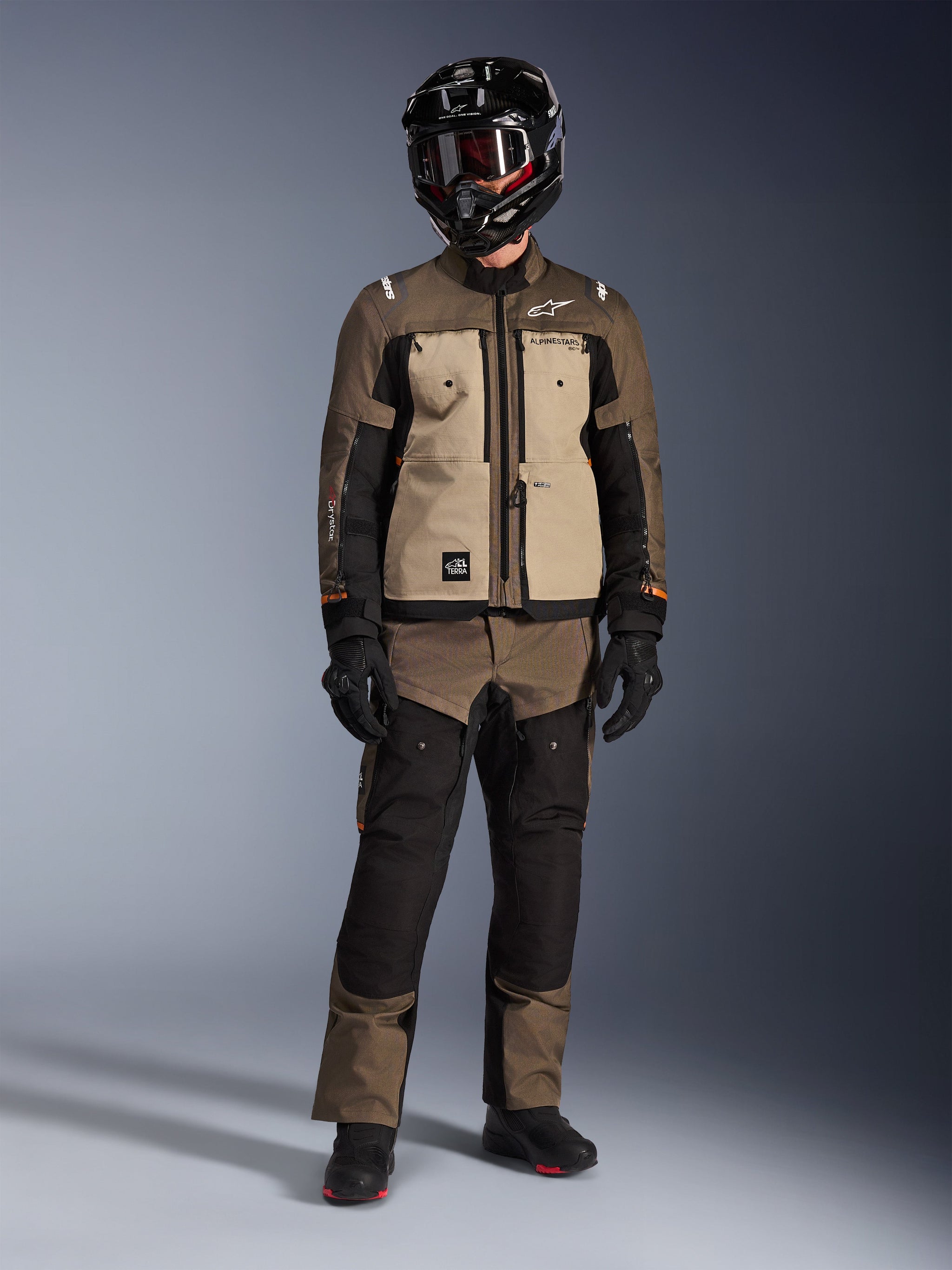 Alpinestars Cusco Drystar® Jacket, Walnut Aluminum Black, adventure touring motorcycle jacket worn with matching pants and a black helmet, featuring tan chest panels and brown ripstop sleeves, technical all-weather riding gear