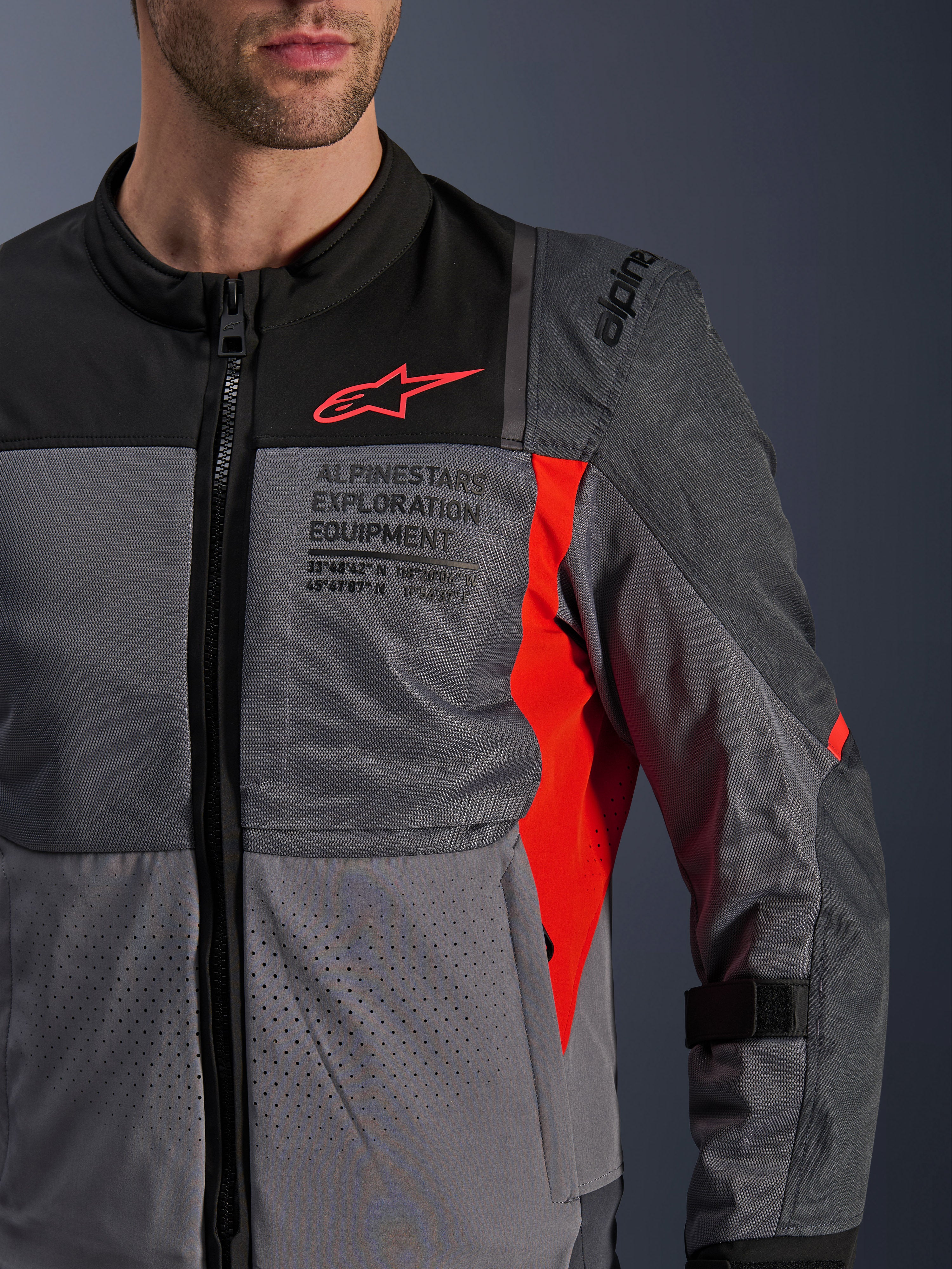 Alpinestars ST-2 Air Jacke, Motorrad-Textiljacke, Tiefgrau und Dunkelgrau mit leuchtend roten Details, Nahaufnahme mit atmungsaktiven Mesh-Einsätzen, laserperforiertem Gewebe und rotem Stern-Logo mit Alpinestars Exploration Equipment Branding.