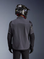 Maxdura Drystar®XF Laminated Armored Shell, Adventure Motorcycle Jacket, Deep Gray Black, rear view showing the technical textile construction and reinforced panels, worn with a black carbon fiber helmet, black riding pants, and gloves