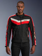 Alpinestars T-Dyno WR Jacke, Textil-Motorradjacke, Schwarz mit leuchtend roten und ecrufarbenen Chevron-Streifen, Vintage-inspirierte Biker-Passform, hoher Kragen mit Knopfverschluss, Reißverschlusstaschen vorne, Sternlogos auf den Ärmeln, von einem Model getragen